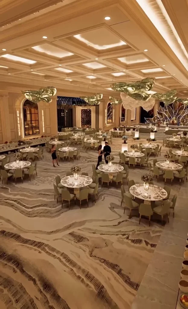 Expansive celebration hall with round tables, coffered ceiling and soft lighting