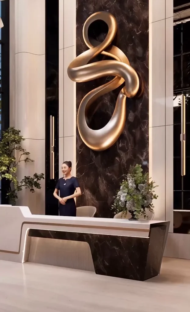 Welcome desk beneath a sculpted bronze installation on dark stone